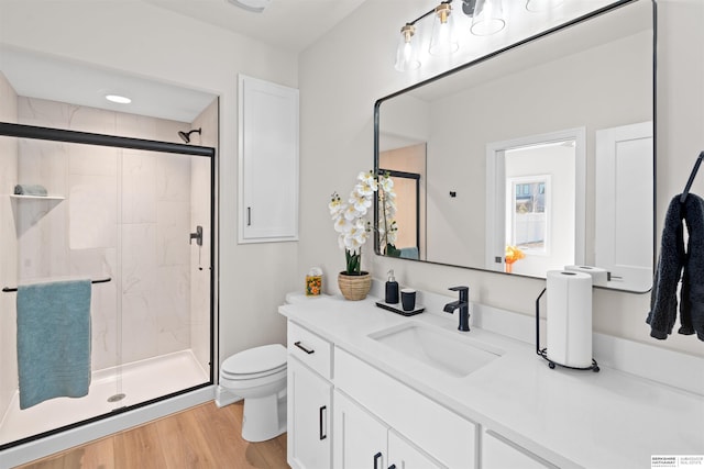 bathroom featuring wood-type flooring, toilet, vanity, and walk in shower