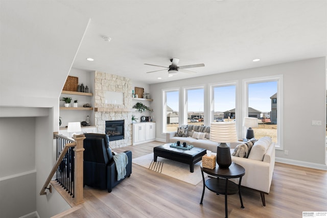 living room with ceiling fan, a fireplace, and light wood-type flooring