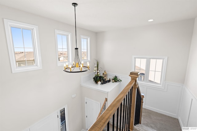 staircase with a healthy amount of sunlight, carpet flooring, and a chandelier