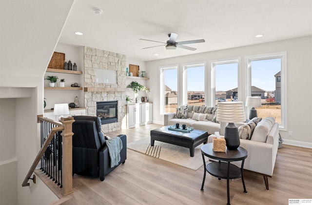 living room featuring ceiling fan, a fireplace, and light hardwood / wood-style flooring