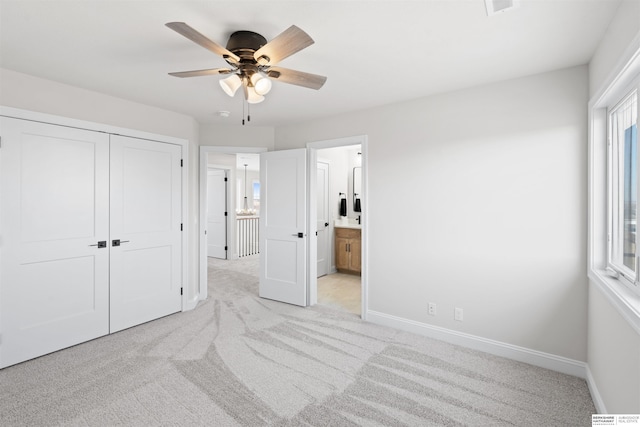 bedroom with light carpet, a closet, ceiling fan, and ensuite bathroom