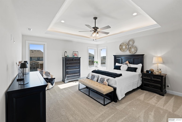 bedroom with ceiling fan, light colored carpet, and a tray ceiling