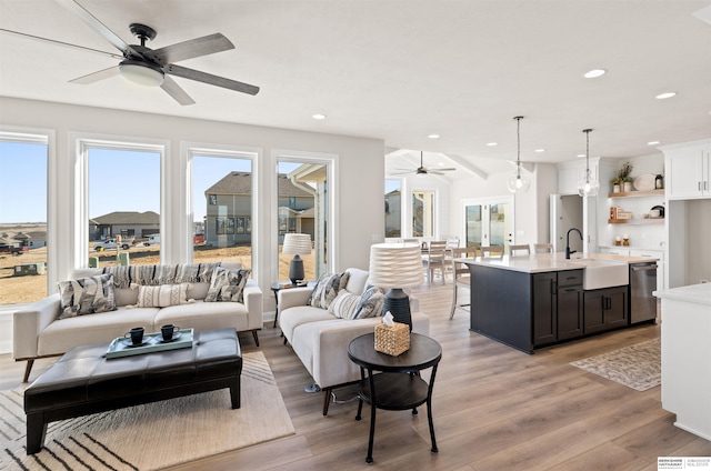 living room with sink, ceiling fan, and light hardwood / wood-style flooring