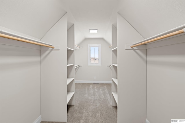 spacious closet with lofted ceiling and light colored carpet