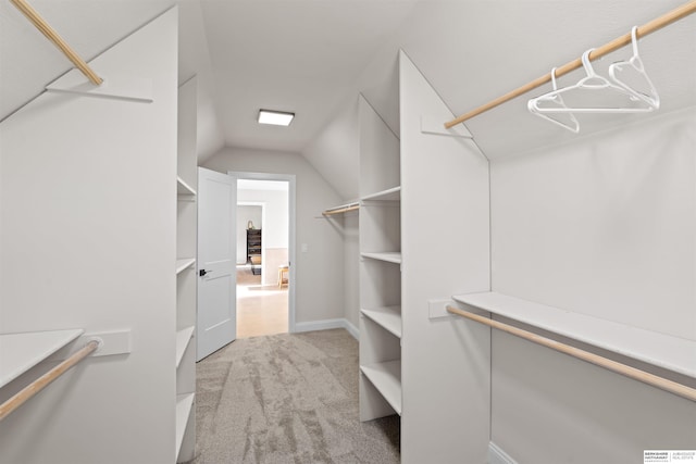 spacious closet featuring lofted ceiling and light colored carpet