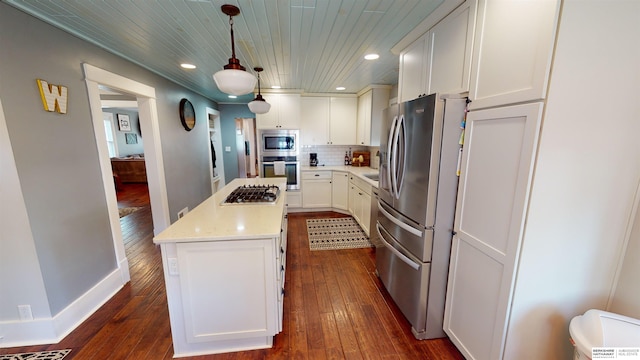 kitchen with a kitchen island, appliances with stainless steel finishes, pendant lighting, tasteful backsplash, and white cabinetry