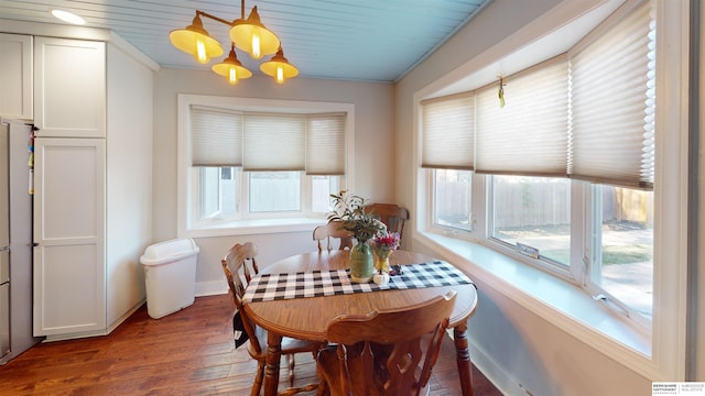 dining area featuring crown molding, an inviting chandelier, and dark hardwood / wood-style flooring