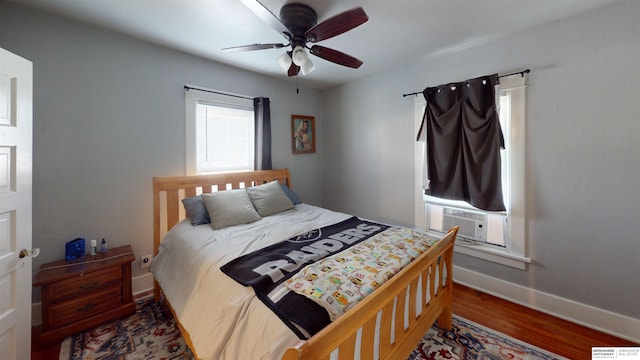 bedroom with cooling unit, dark wood-type flooring, and ceiling fan