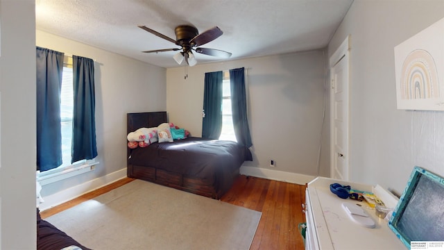 bedroom with a textured ceiling, wood-type flooring, and ceiling fan