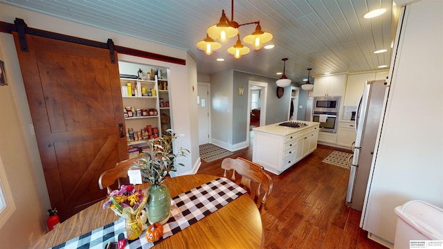 kitchen with a kitchen island, white cabinets, hanging light fixtures, stainless steel appliances, and a barn door