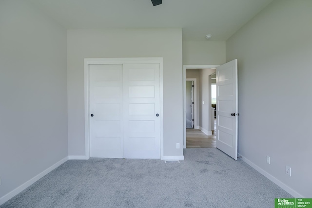 unfurnished bedroom with light colored carpet and a closet