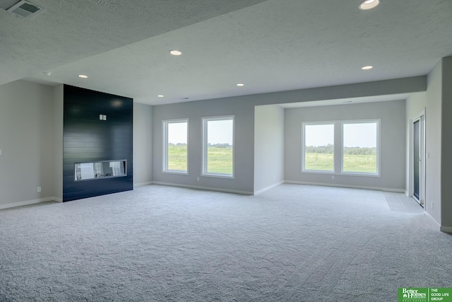 unfurnished living room featuring wood walls, a fireplace, light carpet, and a textured ceiling