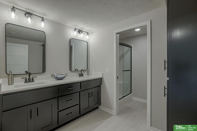 bathroom featuring vanity, a textured ceiling, and a shower with shower door