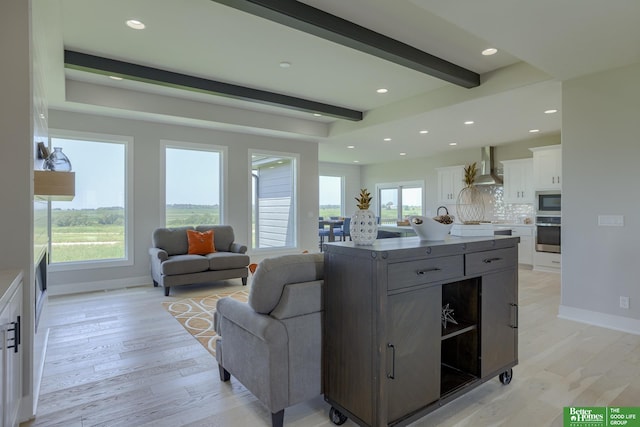 living room with beamed ceiling, light hardwood / wood-style floors, and a healthy amount of sunlight