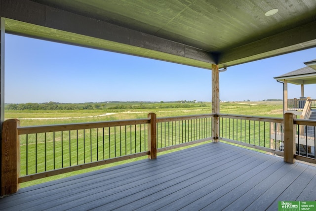 wooden terrace featuring a lawn and a rural view