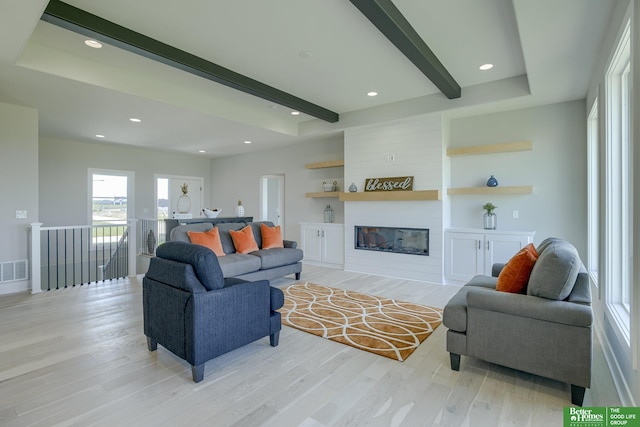 living room with beamed ceiling, a fireplace, and light hardwood / wood-style flooring