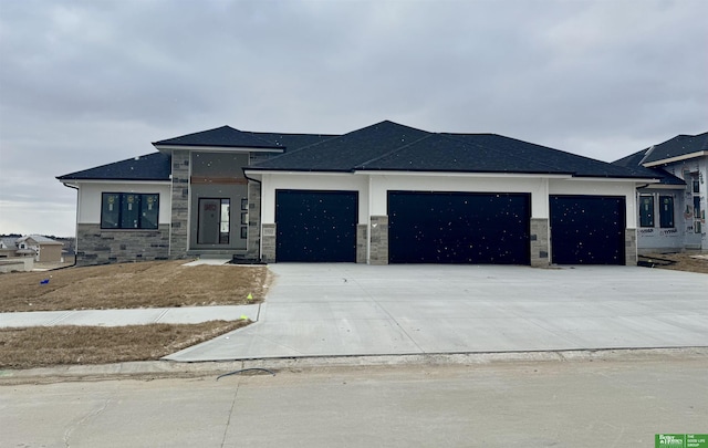 prairie-style home with stone siding, an attached garage, and concrete driveway