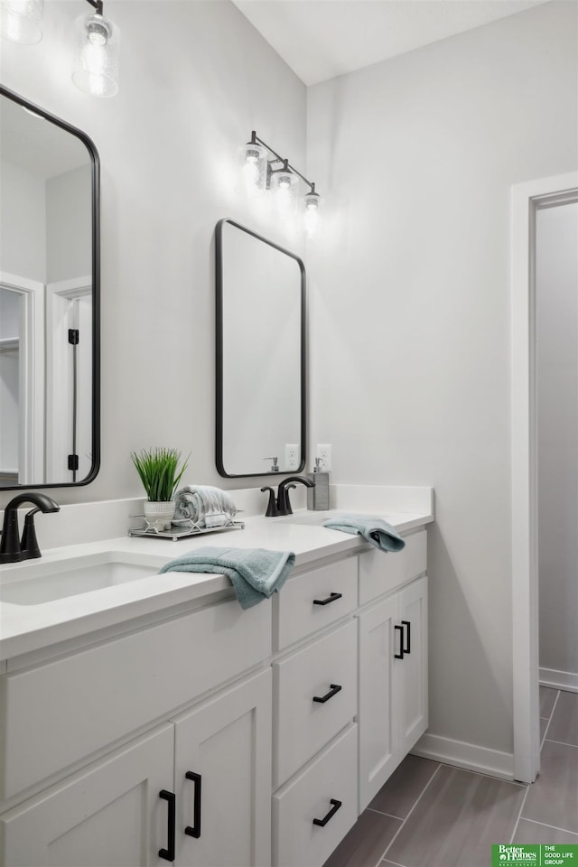 full bathroom featuring double vanity, baseboards, and a sink