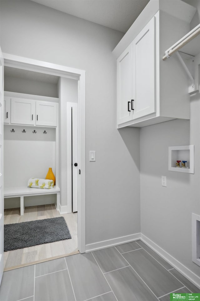 clothes washing area featuring washer hookup, cabinet space, and baseboards