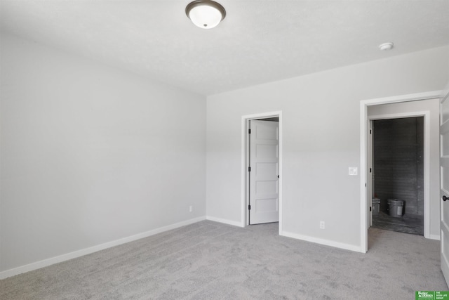 unfurnished bedroom featuring light carpet, a walk in closet, and baseboards