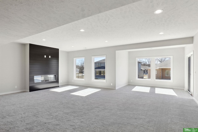 unfurnished living room featuring a healthy amount of sunlight, light colored carpet, and a large fireplace