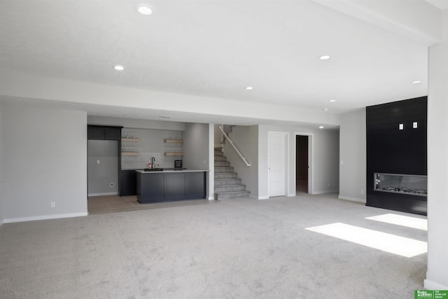 unfurnished living room featuring recessed lighting, light carpet, stairway, and baseboards