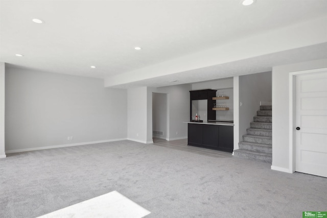 unfurnished living room featuring carpet floors, stairs, baseboards, and recessed lighting