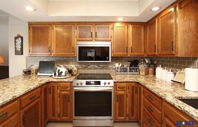 kitchen with electric stove, tasteful backsplash, light stone countertops, and brown cabinets