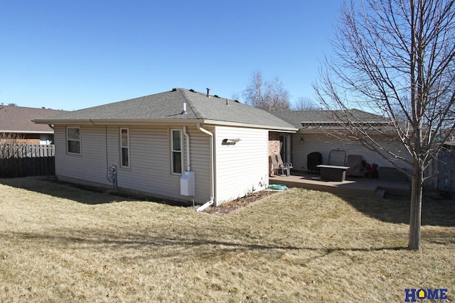 rear view of house with a yard, roof with shingles, a patio, and fence