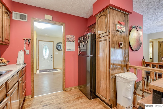 kitchen featuring fridge, a textured ceiling, and light wood-type flooring