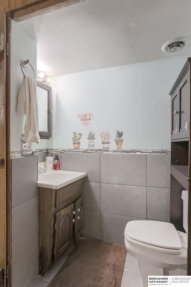 bathroom featuring vanity, tile patterned floors, toilet, and tile walls