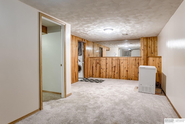 interior space featuring washer / dryer, carpet floors, a textured ceiling, and wood walls