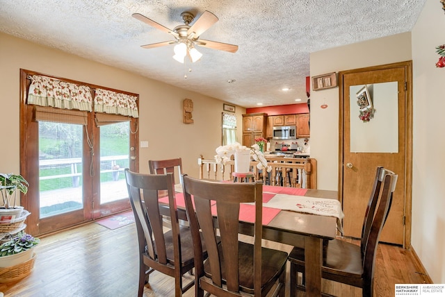 dining area with ceiling fan, a textured ceiling, and light wood-type flooring