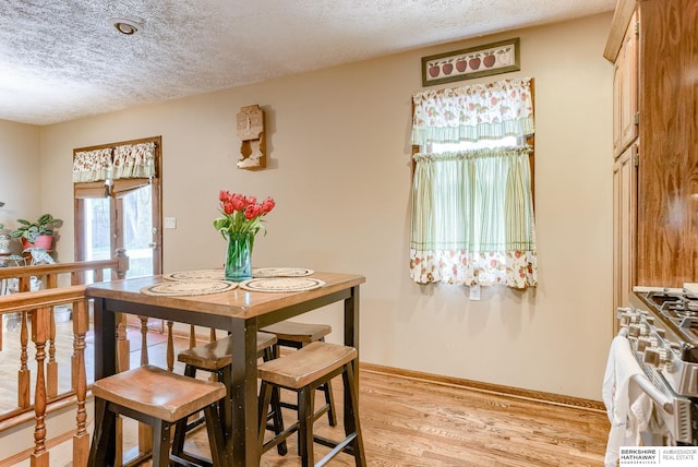 dining space with light hardwood / wood-style floors and a textured ceiling