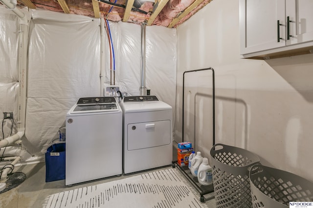 clothes washing area with cabinets and washer and clothes dryer