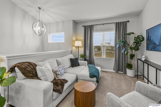 carpeted living room with an inviting chandelier