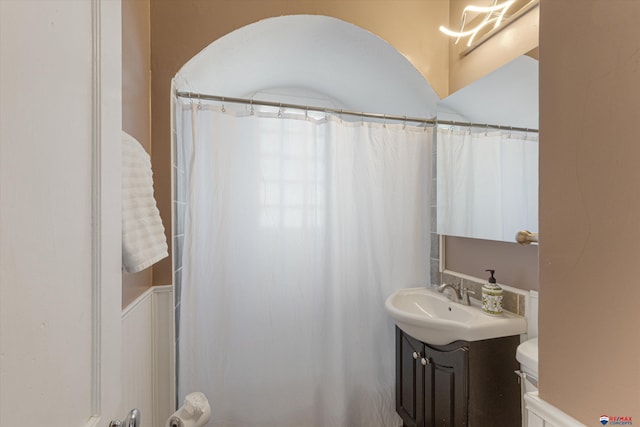 bathroom with walk in shower, vanity, and toilet