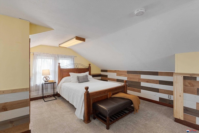 bedroom with lofted ceiling, wooden walls, and light carpet