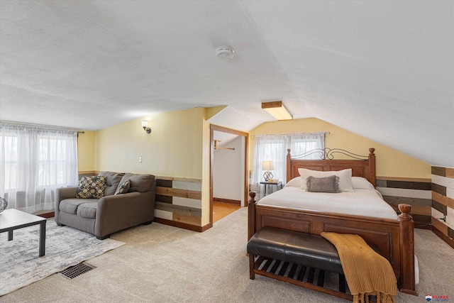 bedroom featuring lofted ceiling, light colored carpet, and a textured ceiling