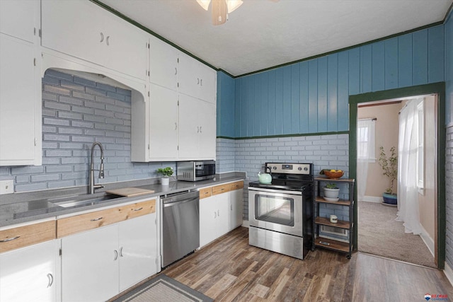 kitchen featuring ornamental molding, appliances with stainless steel finishes, dark hardwood / wood-style floors, and white cabinets