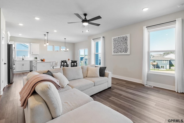 living room with hardwood / wood-style flooring, sink, and ceiling fan with notable chandelier