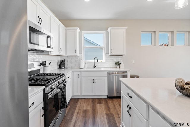 kitchen featuring sink, white cabinetry, stainless steel appliances, dark hardwood / wood-style floors, and tasteful backsplash