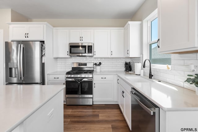 kitchen featuring appliances with stainless steel finishes, white cabinetry, sink, backsplash, and dark hardwood / wood-style flooring