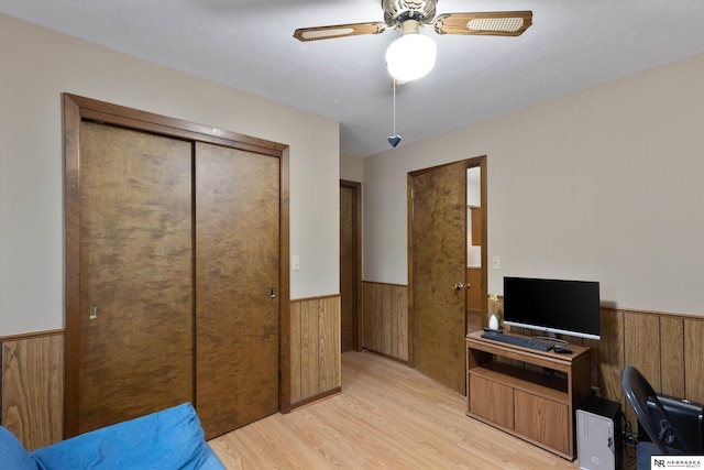 office area featuring ceiling fan, wooden walls, and light hardwood / wood-style flooring