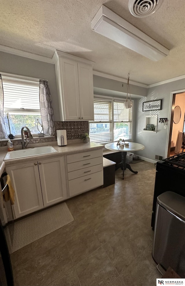 kitchen featuring crown molding, sink, white cabinets, and decorative light fixtures