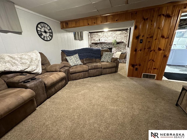 living room with wood walls, washing machine and clothes dryer, and carpet flooring