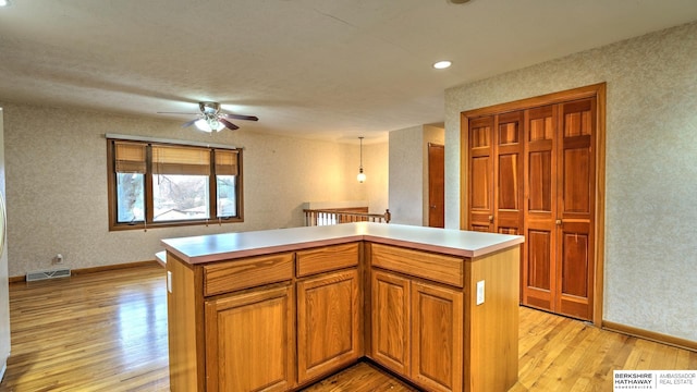 kitchen with a kitchen island, pendant lighting, and light hardwood / wood-style floors