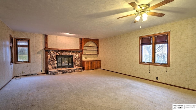 unfurnished living room with ceiling fan, light carpet, a textured ceiling, and a fireplace