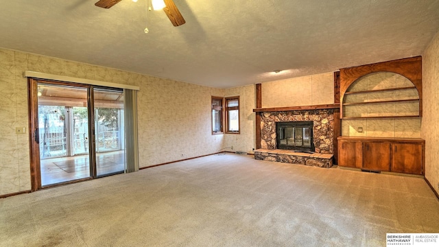 unfurnished living room featuring ceiling fan, plenty of natural light, carpet floors, and a fireplace