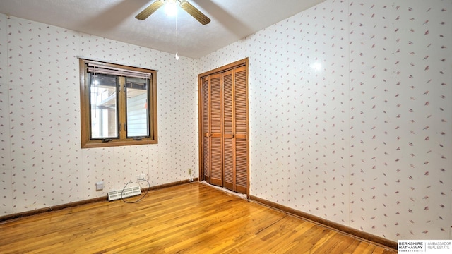 unfurnished bedroom with hardwood / wood-style floors, a closet, and ceiling fan